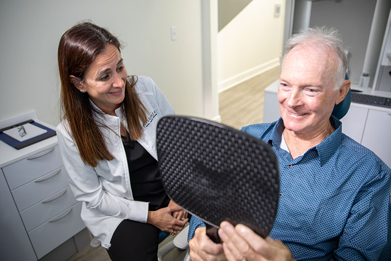 Patient looking into a mirror to see their new smile